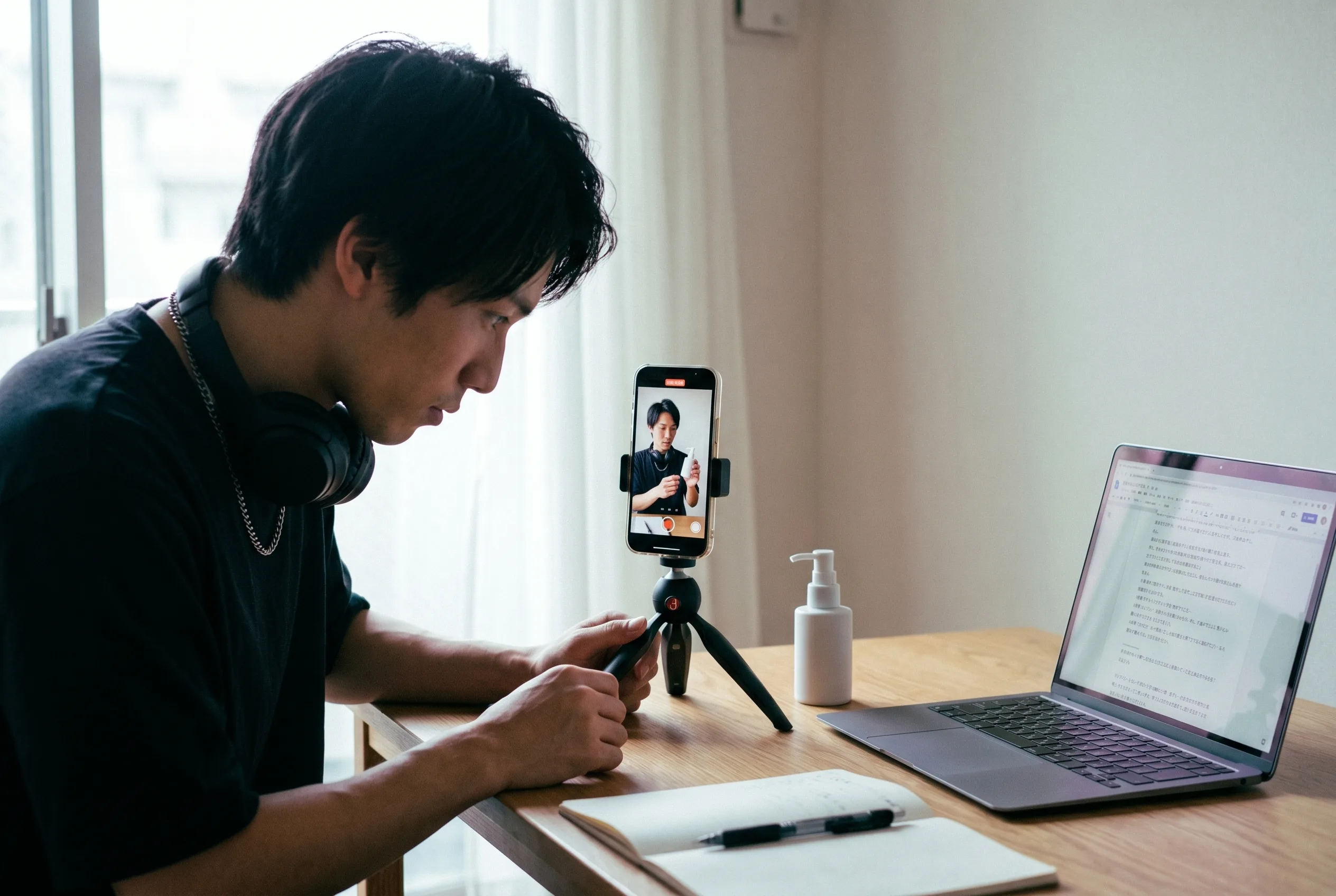 How to make AI UGC in practice: a creator at his desk mid-production with a phone on a small tripod showing a vertical UGC frame of himself, a script document open on the laptop beside it, rendered by the Playcut Actor Engine